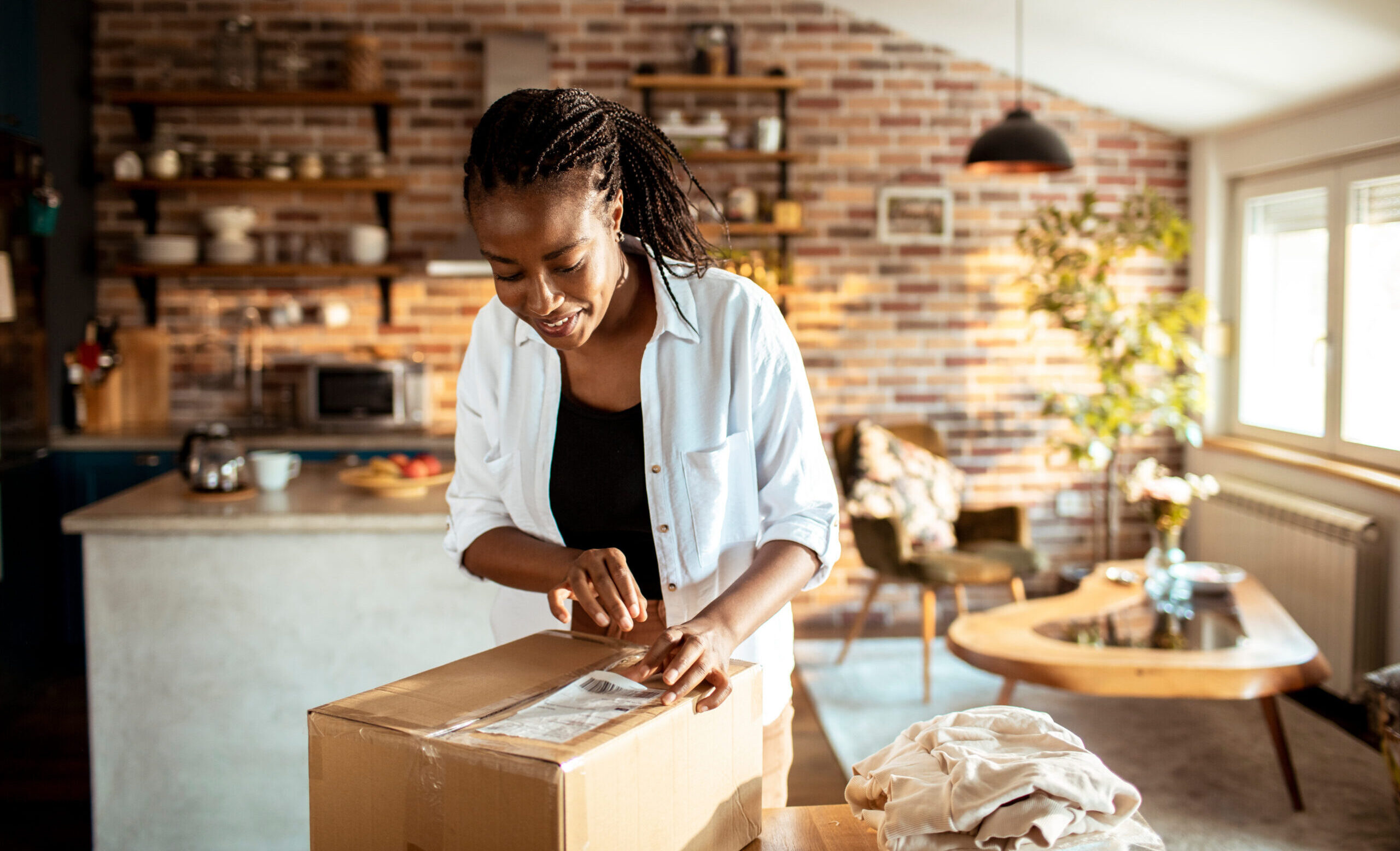 Young woman opening up the package she received in the mail at home in the kitchen